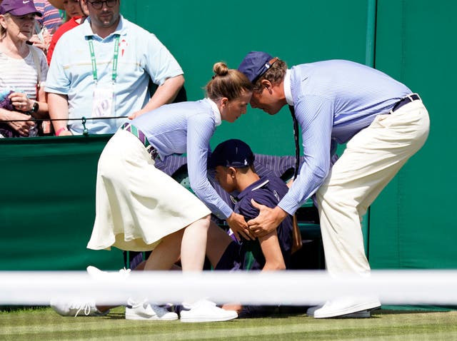 Line staff assist a ballboy who fainted in the heat