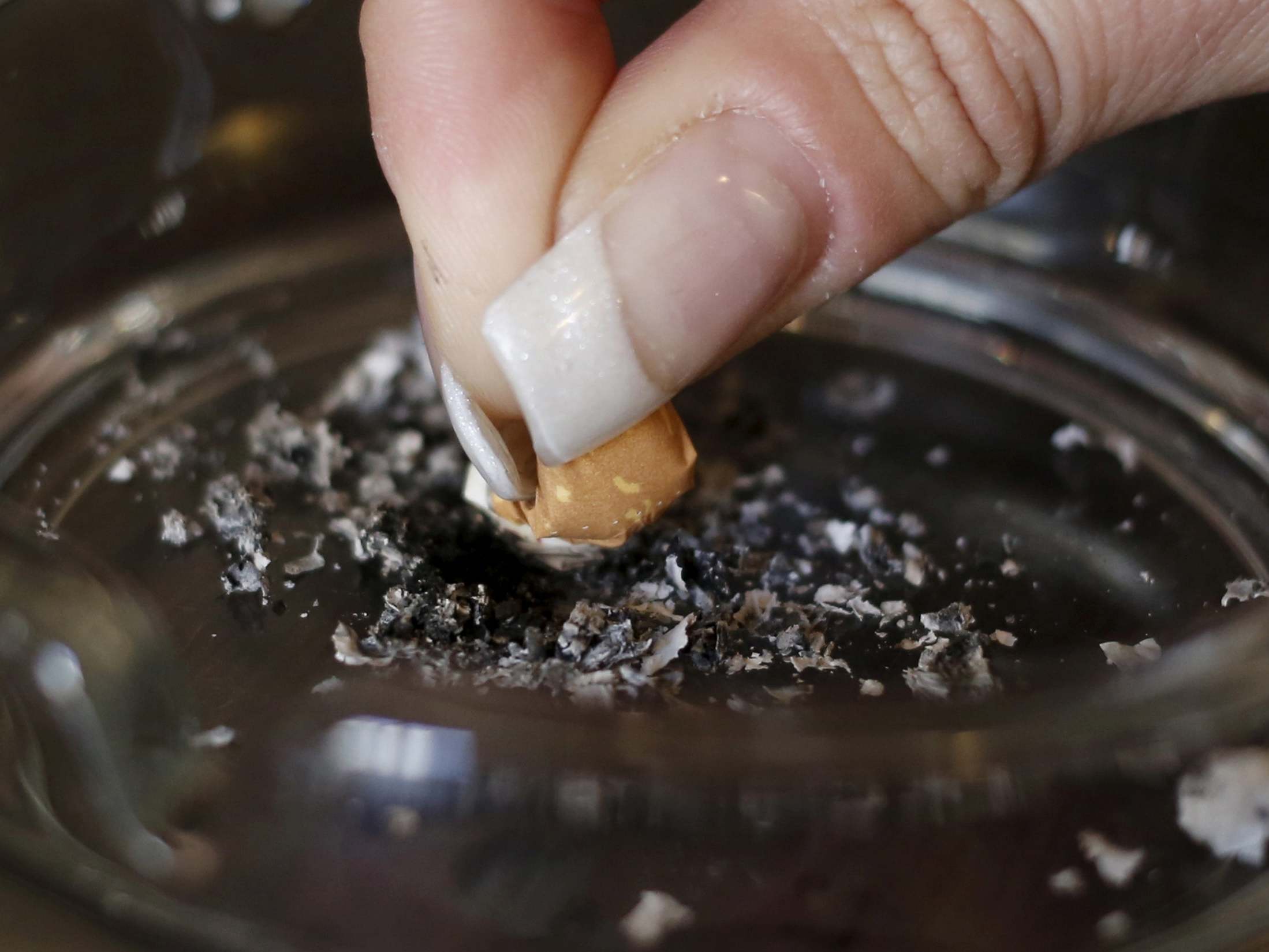 A woman stubs out a cigarette in an ashtray in a cafe