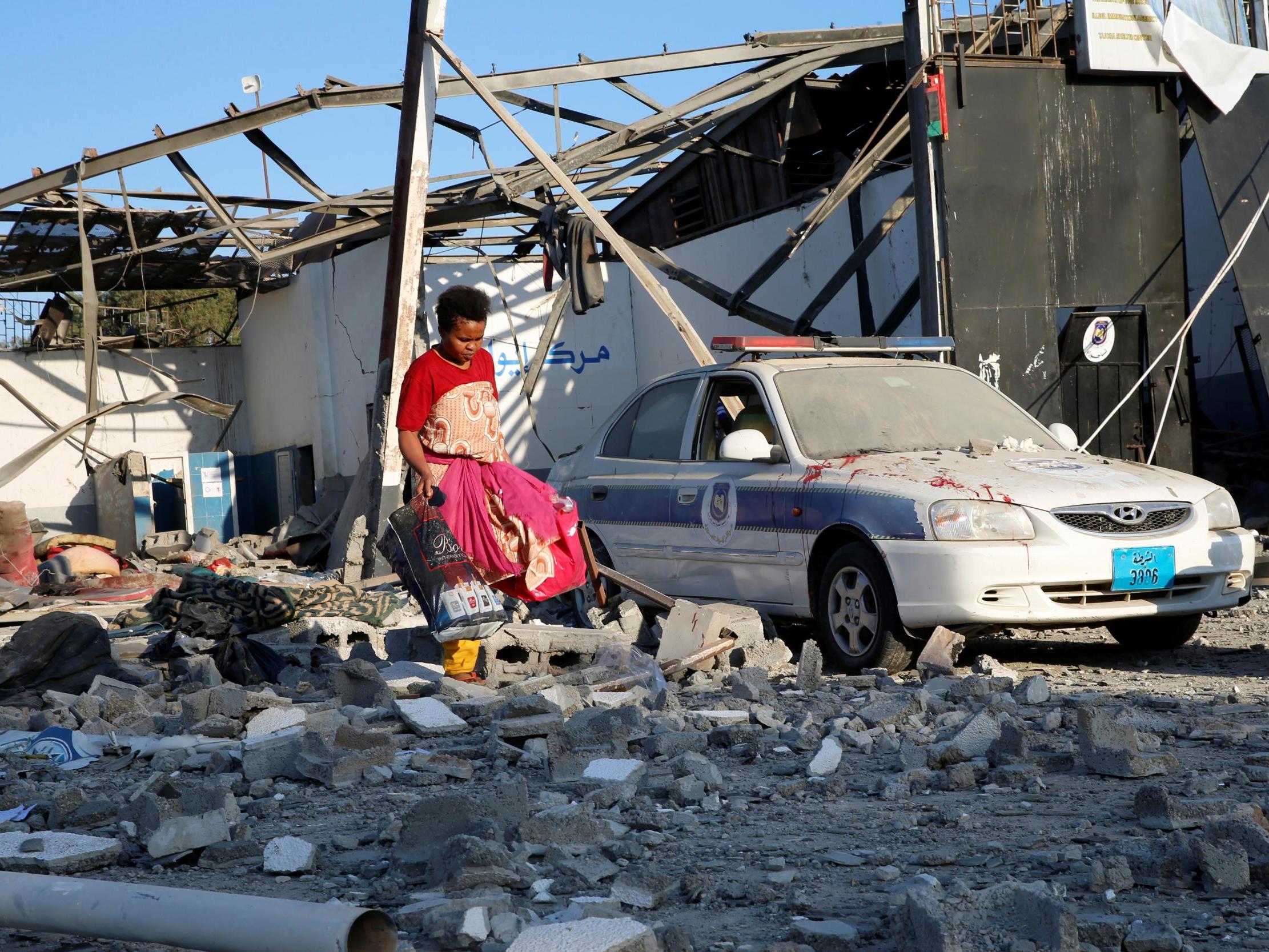 A migrant picks up clothes from among rubble at a detention centre for mainly African migrants that was hit by an airstrike in the Tajoura suburb of the Libyan capital of Tripoli, Libya July 3, 2019.