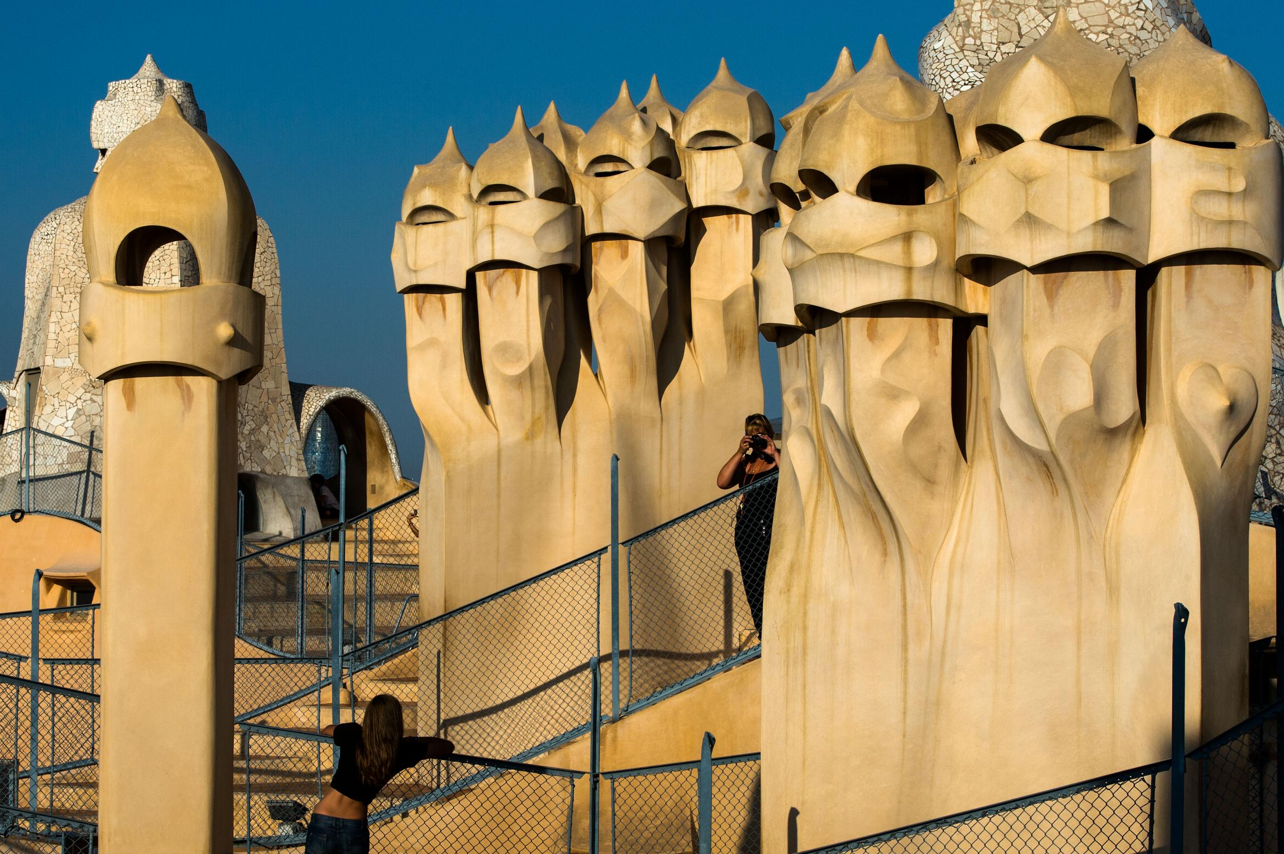 Tourists pose for pictures on the roof terrace of La Pedrera, with its chimneys shaped like helmets (Getty)