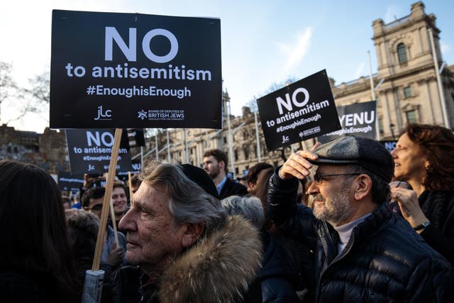 Protesters hold placards as they demonstrate in Parliament Square, London, against antisemitism.