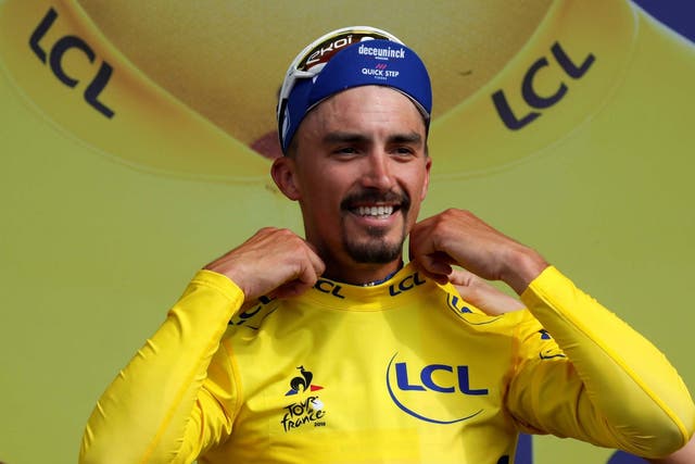 Julian Alaphilippe on the podium wearing the yellow jersey