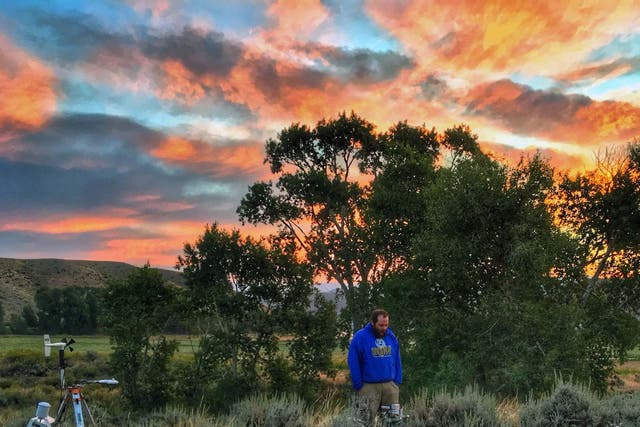 Daniel Beverly, a PhD candidate at the University of Wyoming, checks on sagebrush and instruments at sunrise near Yellowstone National Park