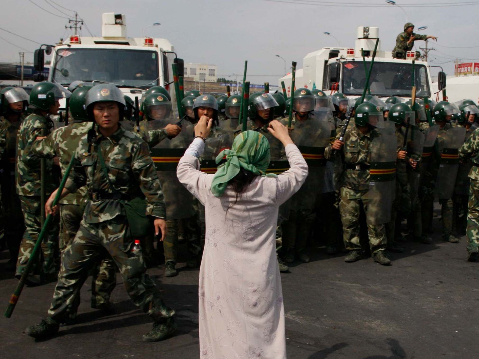 An Uighur woman protests before a group of paramilitary police when journalists visited Xinjiang in July, 2009