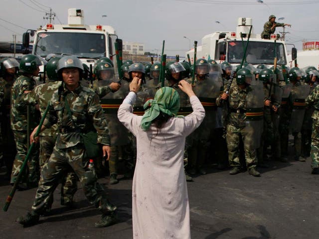 An Uighur woman protests before a group of paramilitary police when journalists visited Xinjiang in July 2009