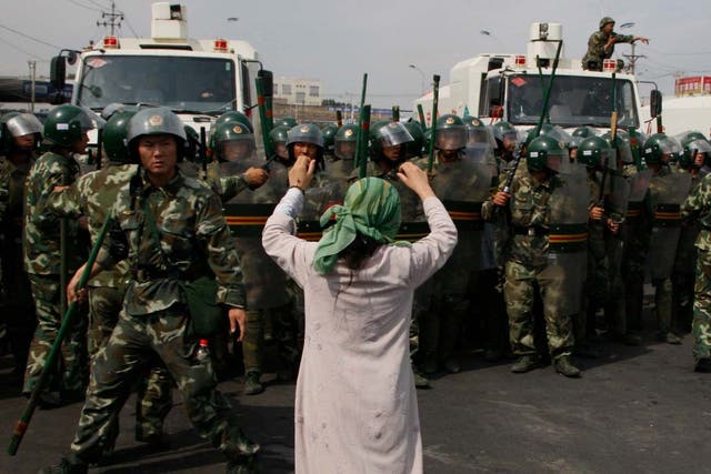 An Uighur woman protests before a group of paramilitary police when journalists visited Xinjiang in July 2009