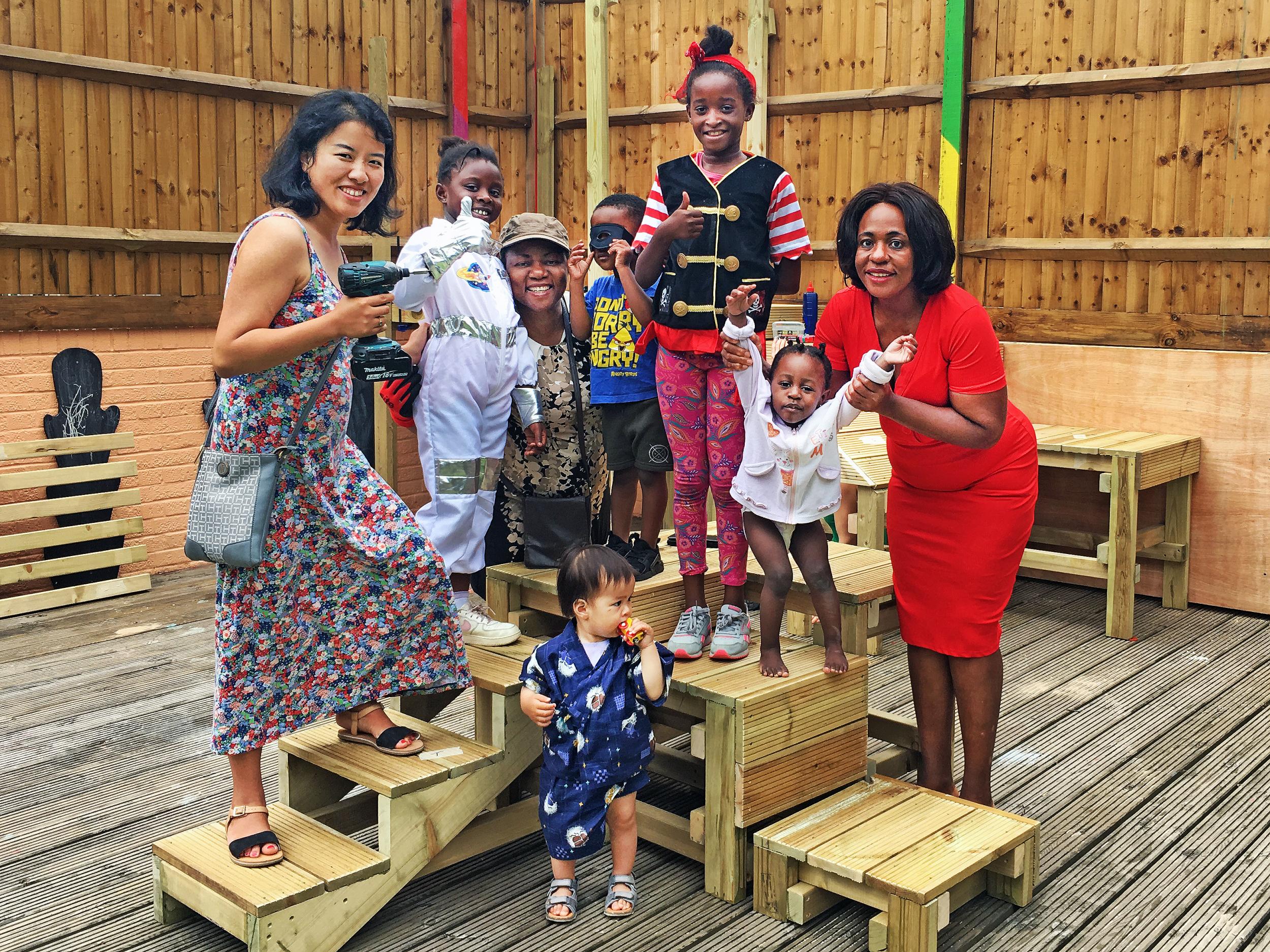 Parents and children build garden furniture ready for the opening of a parent-led nursery in Deptford, South London