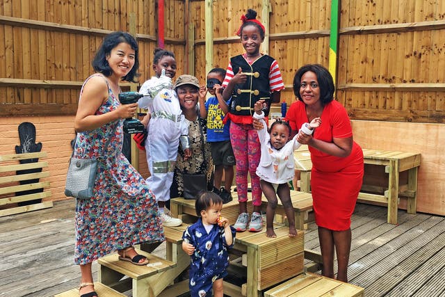 Parents and children build garden furniture ready for the opening of a parent-led nursery in Deptford, South London