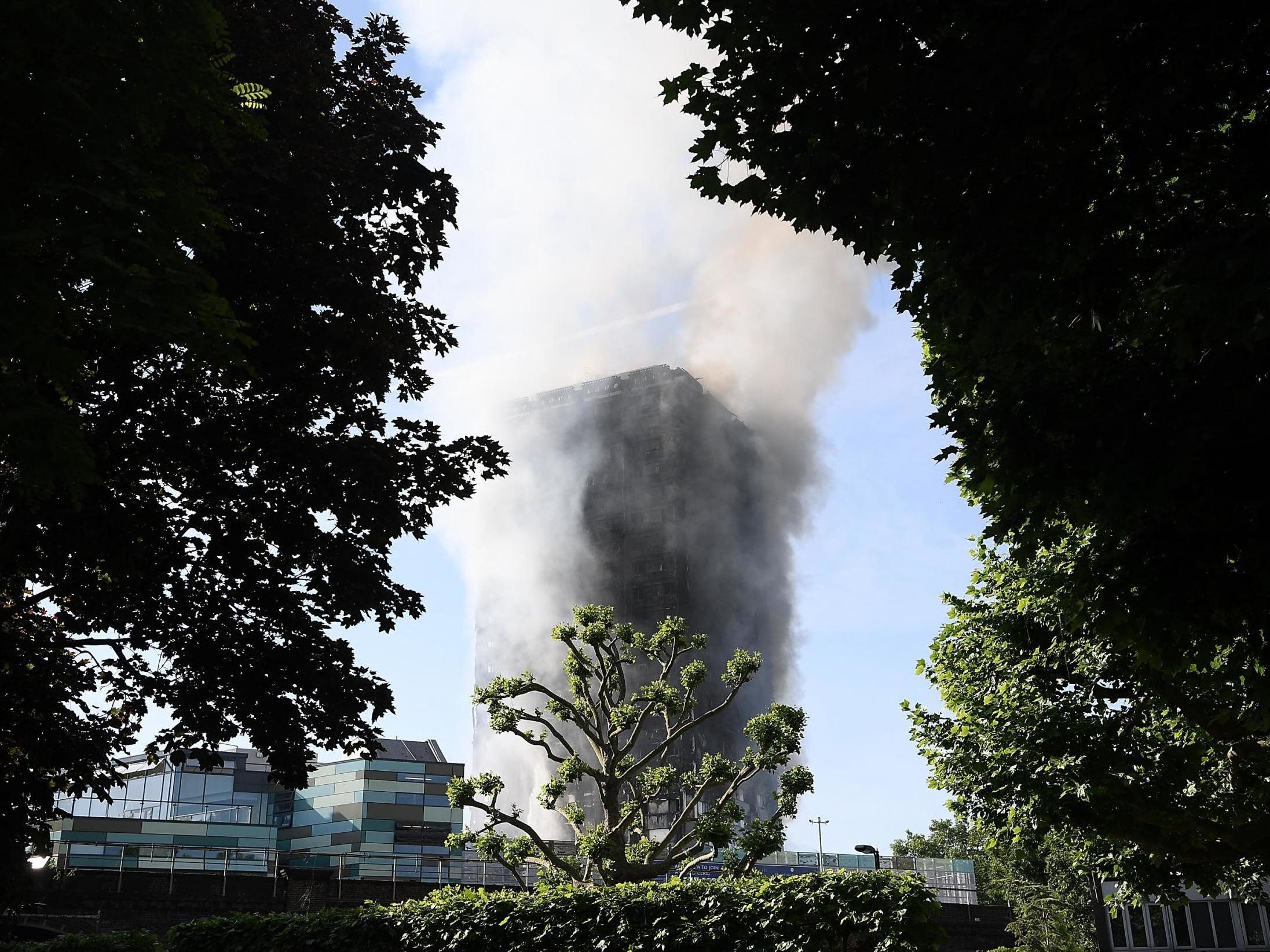 Smoke rises from the building after a huge fire engulfed the 24 storey residential Grenfell Tower block in Latimer Road, West London in the early hours of June 14, 2017 in London, England