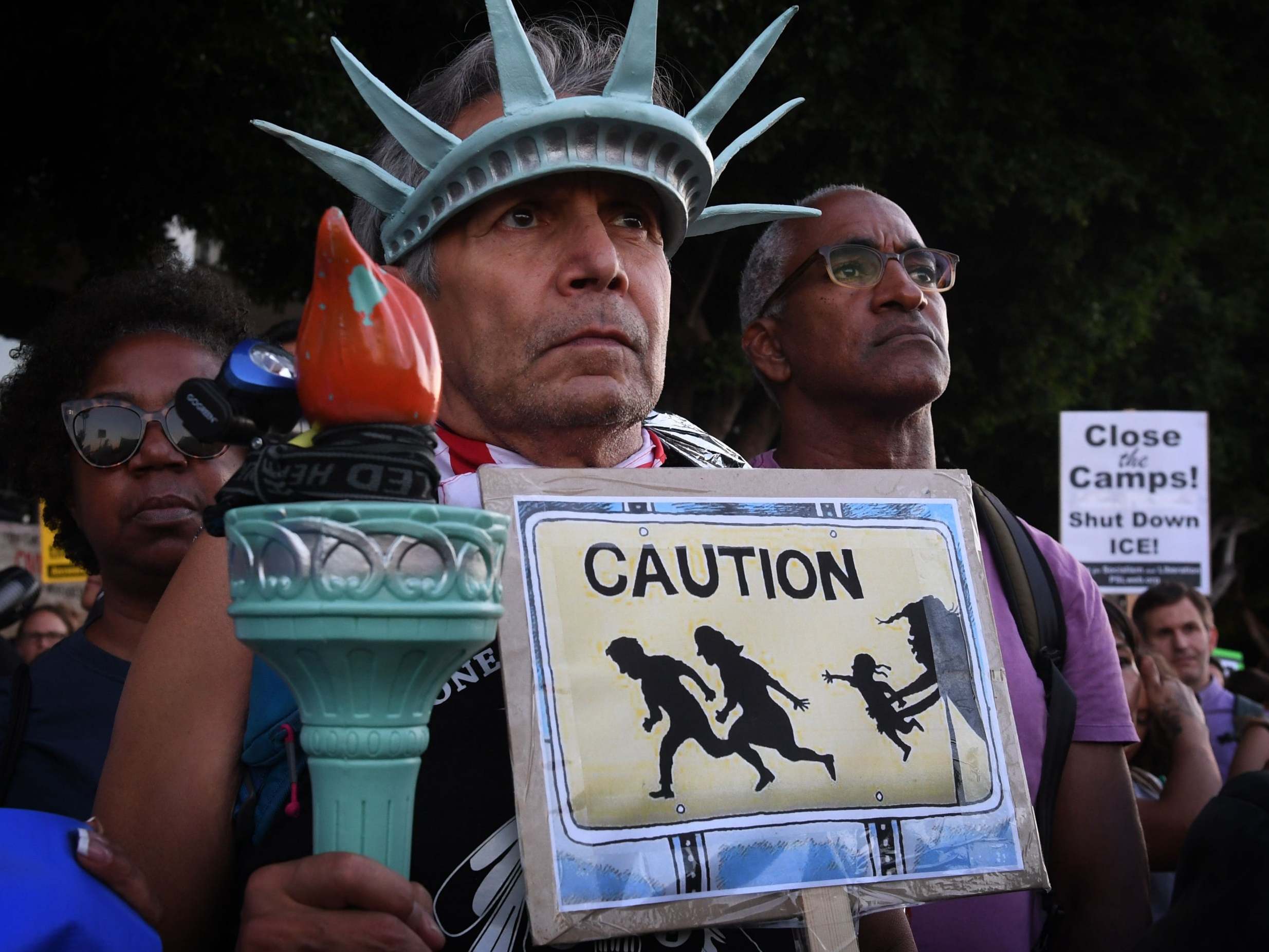 A man wears a Statue of Liberty crown during protests against the raids and detentions of asylum-seekers at a vigil in Los Angeles