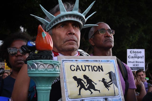 A man wears a Statue of Liberty crown during protests against the raids and detentions of asylum-seekers at a vigil in Los Angeles