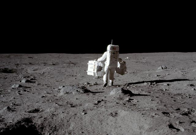 Apollo 11 lunar module pilot Buzz Aldrin carries equipment for the Passive Seismic Experiments (in his left hand) and the Laser Ranging Retroreflector (in his right) to the deployment area at Tranquility Base in the Sea of Tranquility on the moon, July 20, 1969