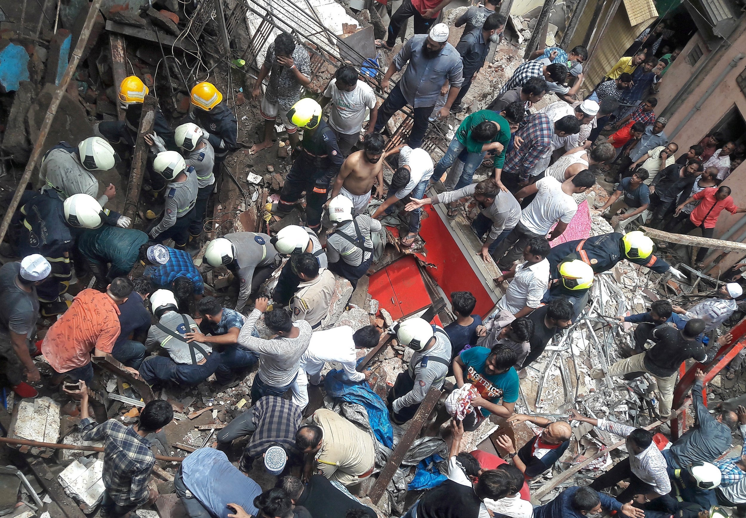 Rescue workers and residents search for survivors at the site of a collapsed building in Mumbai, India,