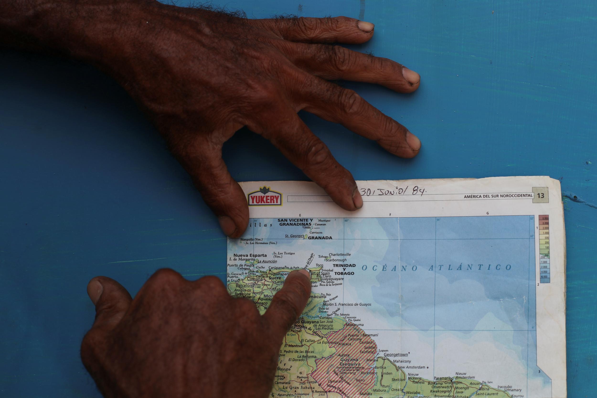 A local resident points on a map at the area where Maroly Bastardo, an eight-months-pregnant woman, disappeared in the Caribbean Sea along with her children, her husband's sister, uncle (Reuters)