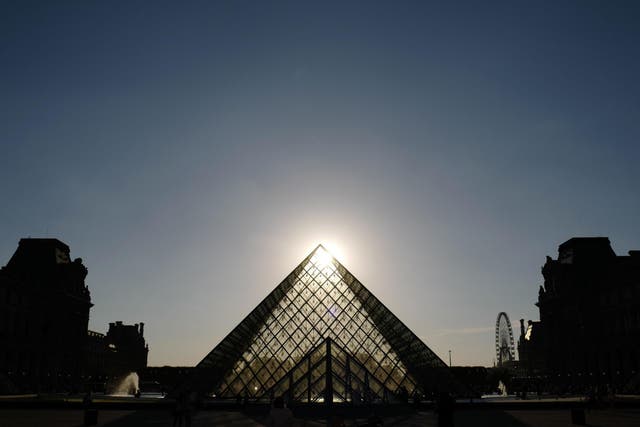 The sun sets behind the Pyramid of the Louvre museum in Paris on 3 July, 2019.