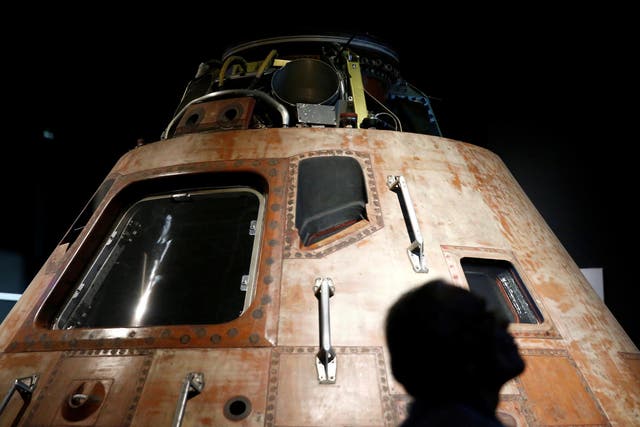 A visitor is silhouetted against the Apollo 11 Command Module "Columbia" at the "Destination Moon: The Apollo 11 Mission" exhibit on the anniversary of the Apollo 11 mission launch at the Museum of Flight in Seattle, Washington