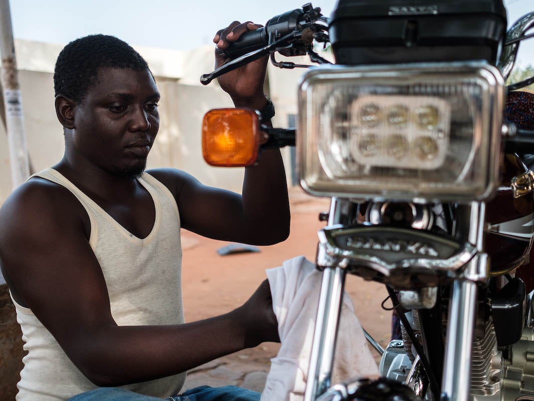 A zémidjan (motorcycle taxi) rider in Lomé obsessively cleaning his bike
