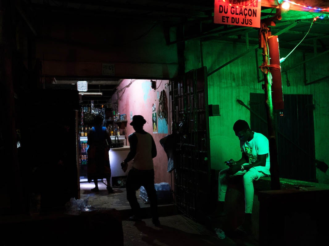 Ayao waiting outside a bar while his friend goes inside to buy alcohol