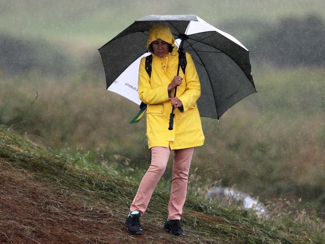 Spectator shields themselves from the rain during day one of The Open Championship 2019 at Royal Portrush Golf Club