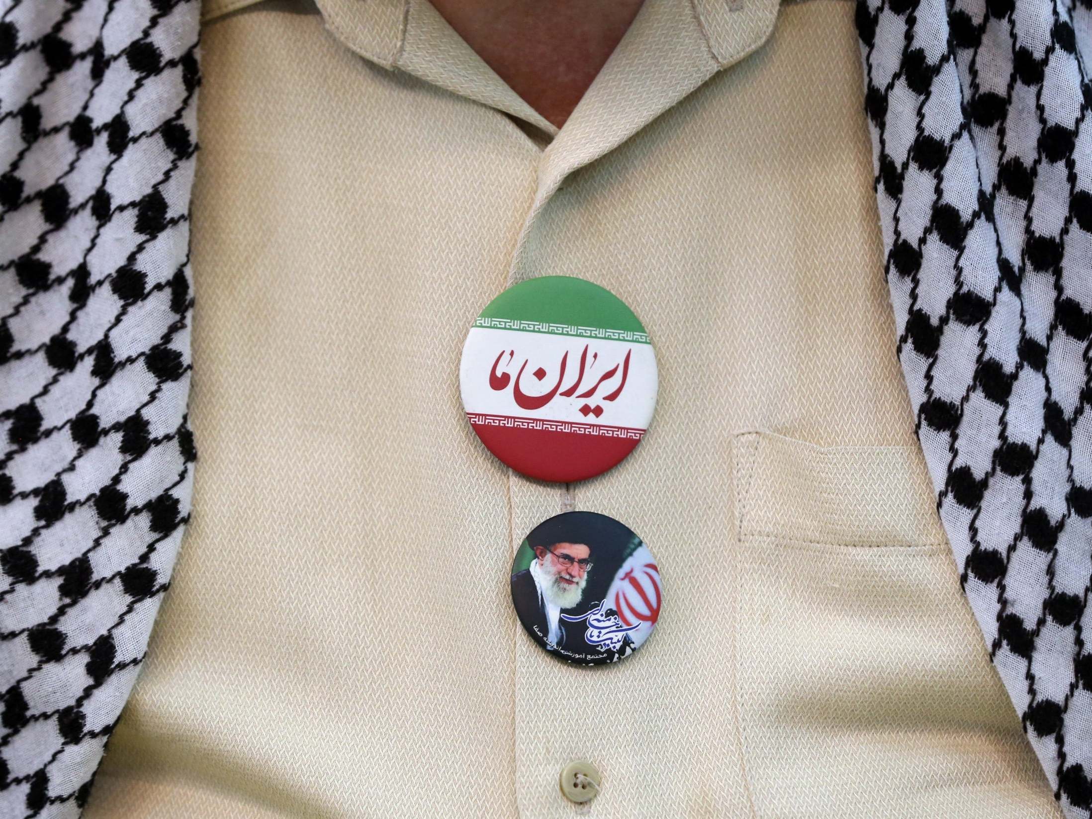 An Iranian man wears a badge of the supreme leader at Friday prayers