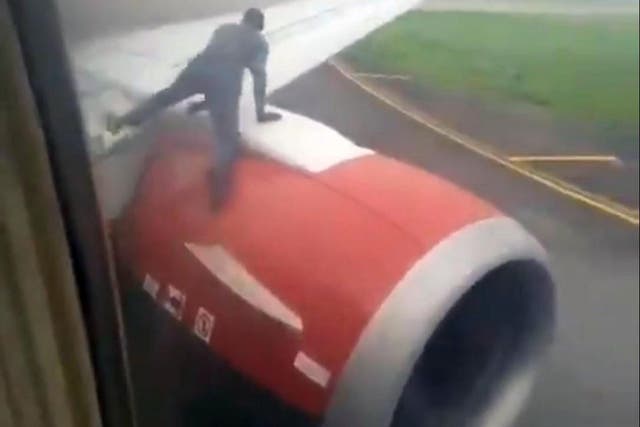 The man clambers over the plane's engine on to the wing