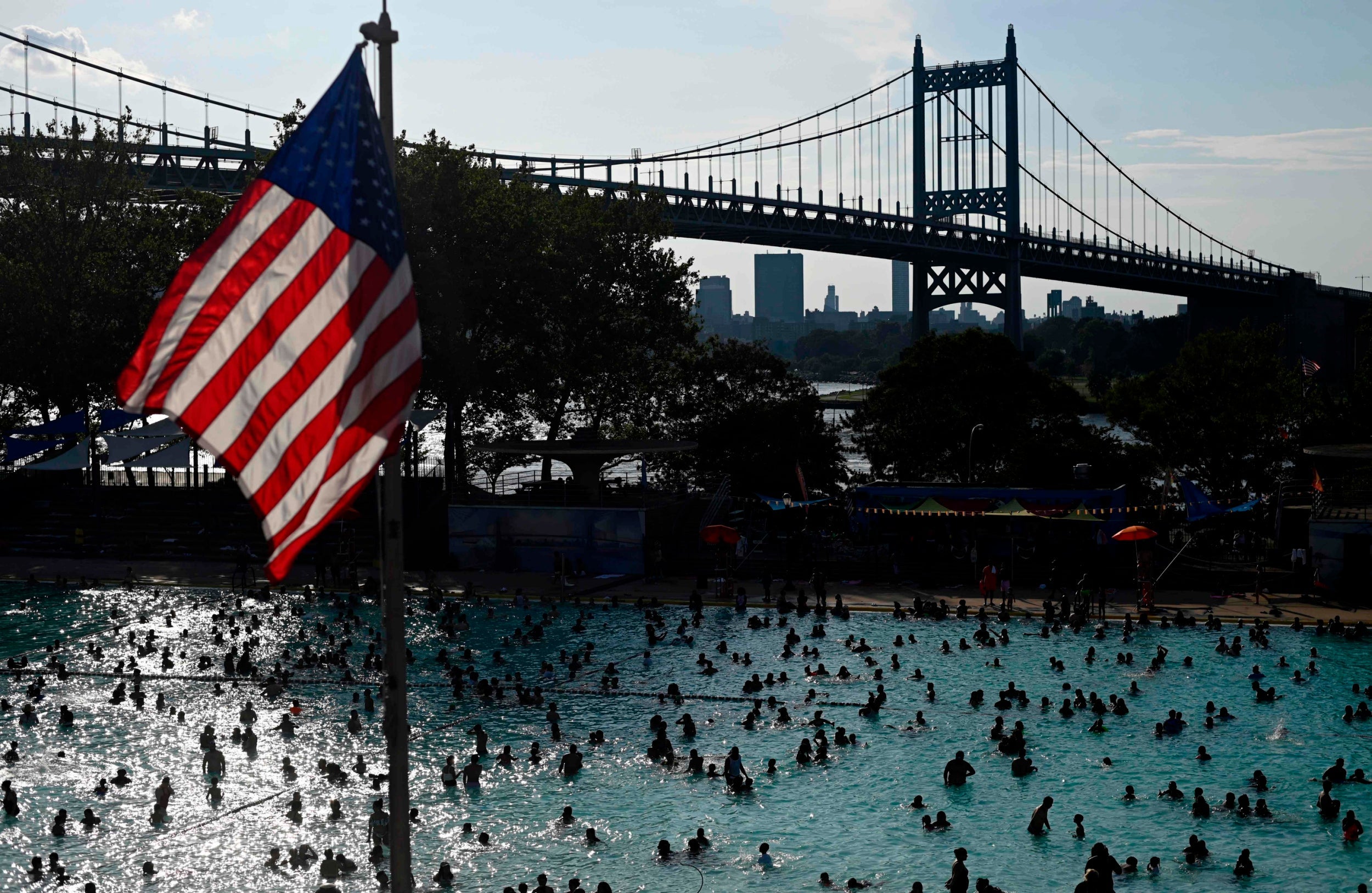 A US flag flies overhead as people enjoy the Astoria Pool on a hot afternoon in the New York City borough of Queens