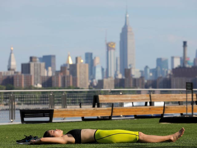 A woman lies in Domino Park as a heatwave continues to affect the region in Brooklyn