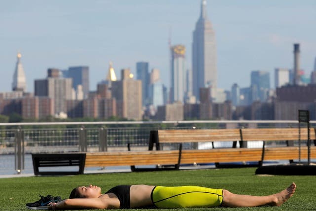 A woman lies in Domino Park as a heatwave continues to affect the region in Brooklyn