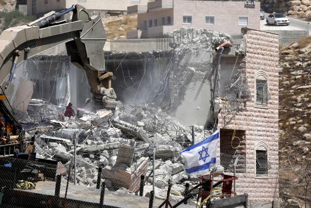 An Israeli army excavator machine demolishes a building in the Palestinian village of Sur Baher, in East Jerusalem