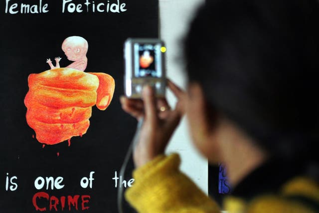 A young girl takes a photograph at an exhibition on female foeticide in Amritsar, India, where sex-selection abortions are illegal but remain common