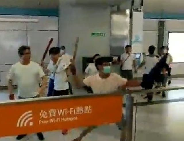 Men in white T-shirts and face masks attack anti-extradition bill demonstrators and reporters at a train station in Hong Kong, China