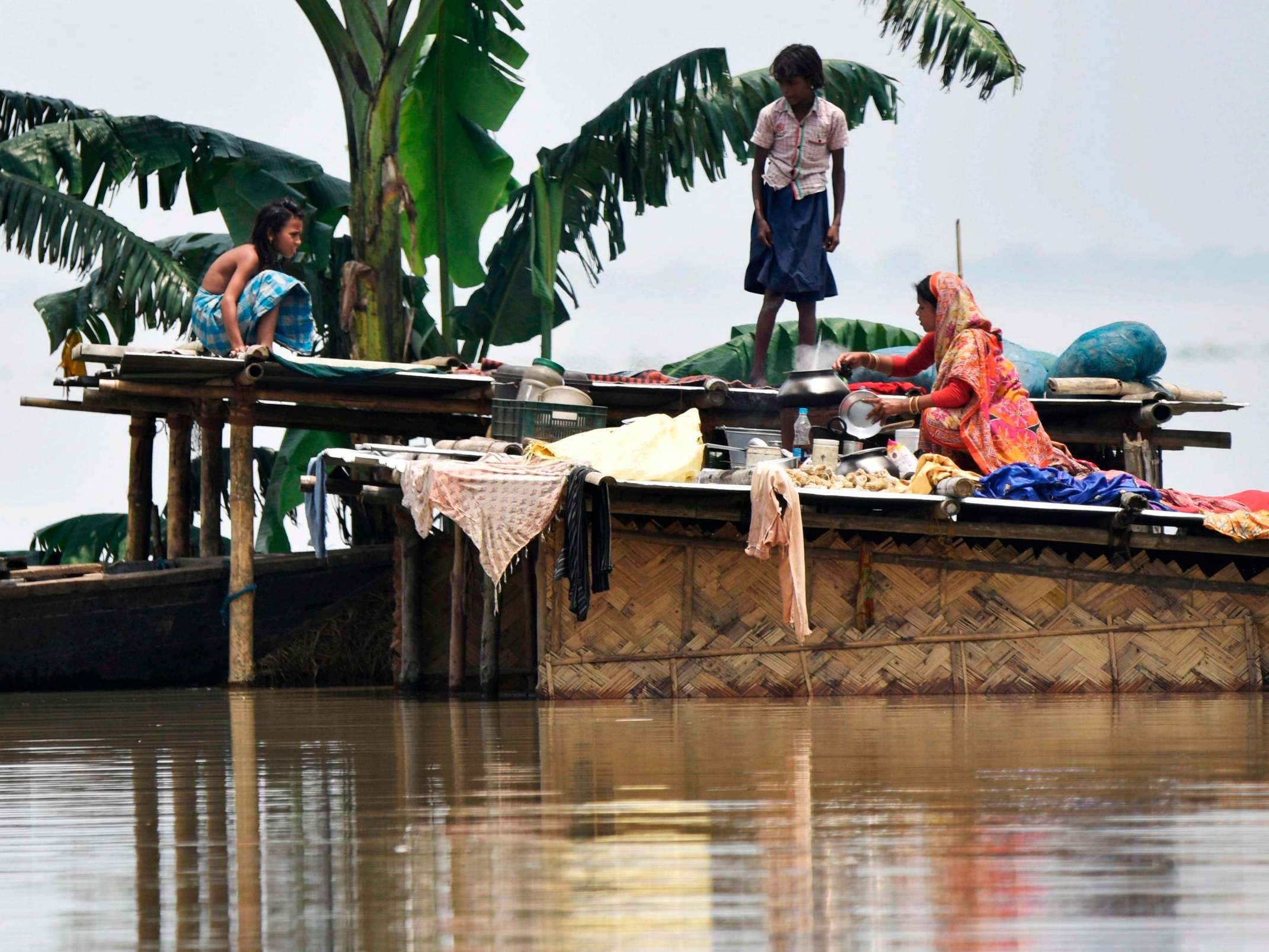 A family take refuge atop a hut in flood-affected Hatishila in India's Assam state