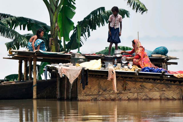 A family take refuge atop a hut in flood-affected Hatishila in India's Assam state
