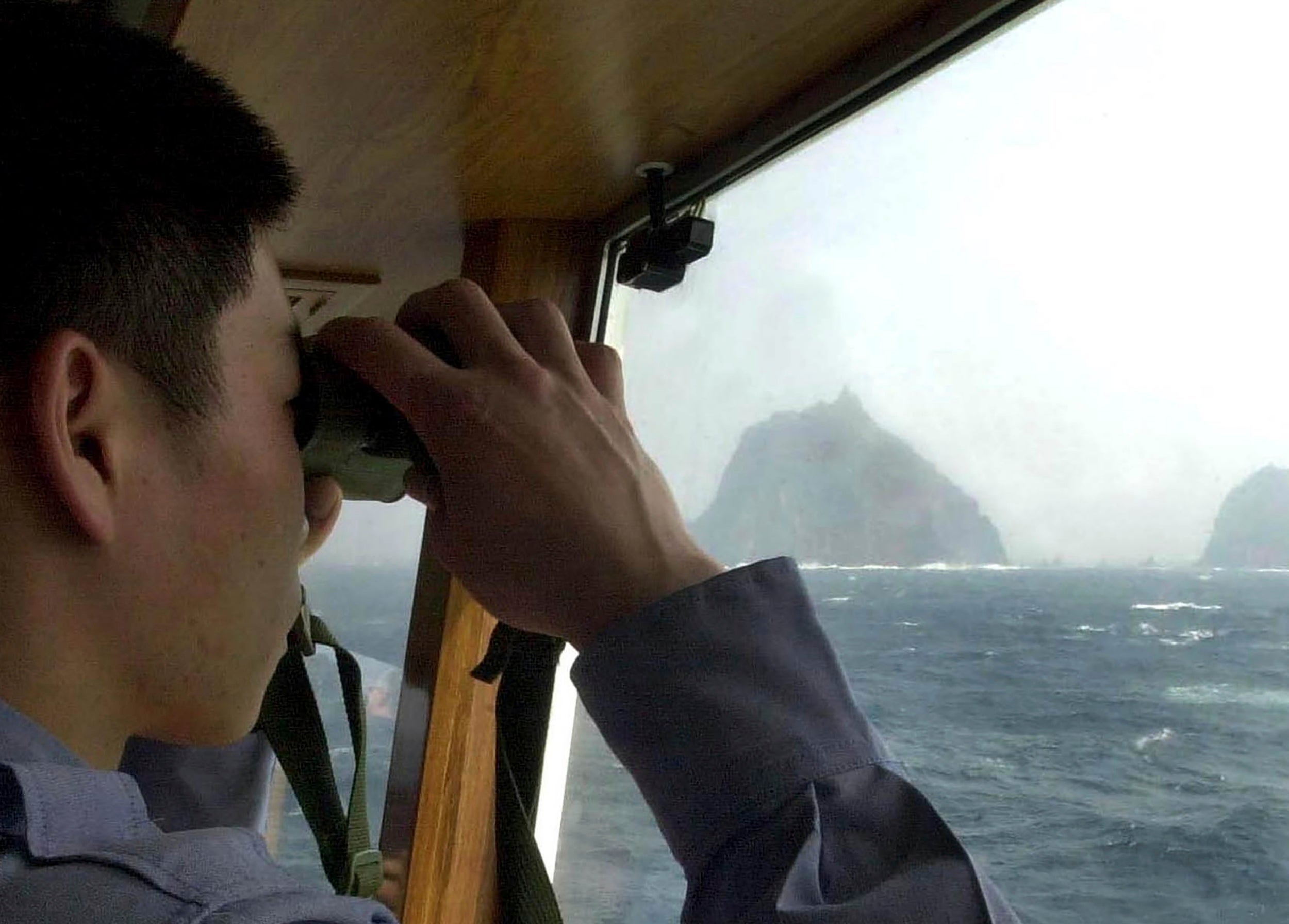File image shows a South Korean coast guard looking out at the Dokdo islets on a patrol ship in the East Sea, South Korea