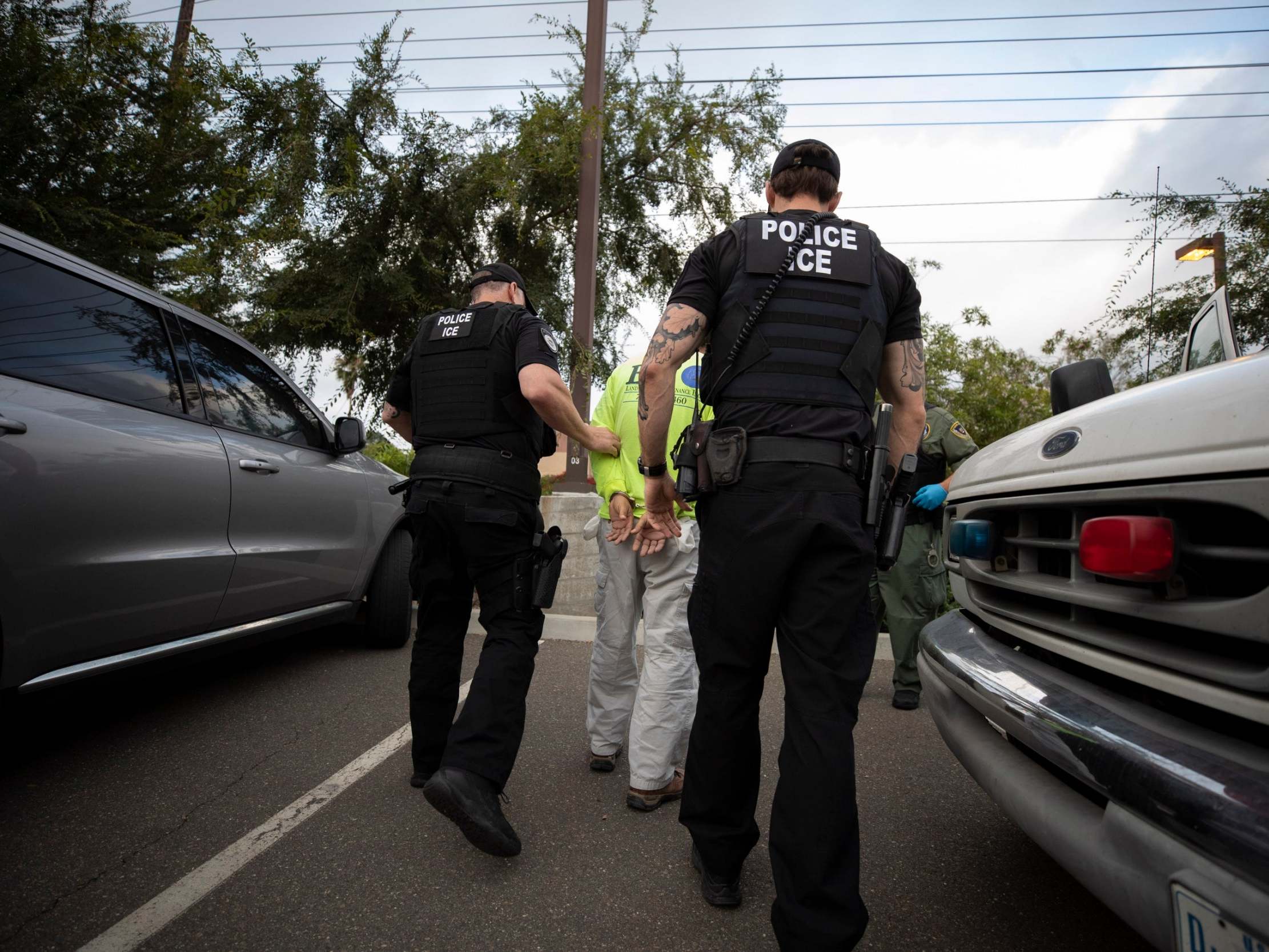 ICE agents escort a man in handcuffs in California