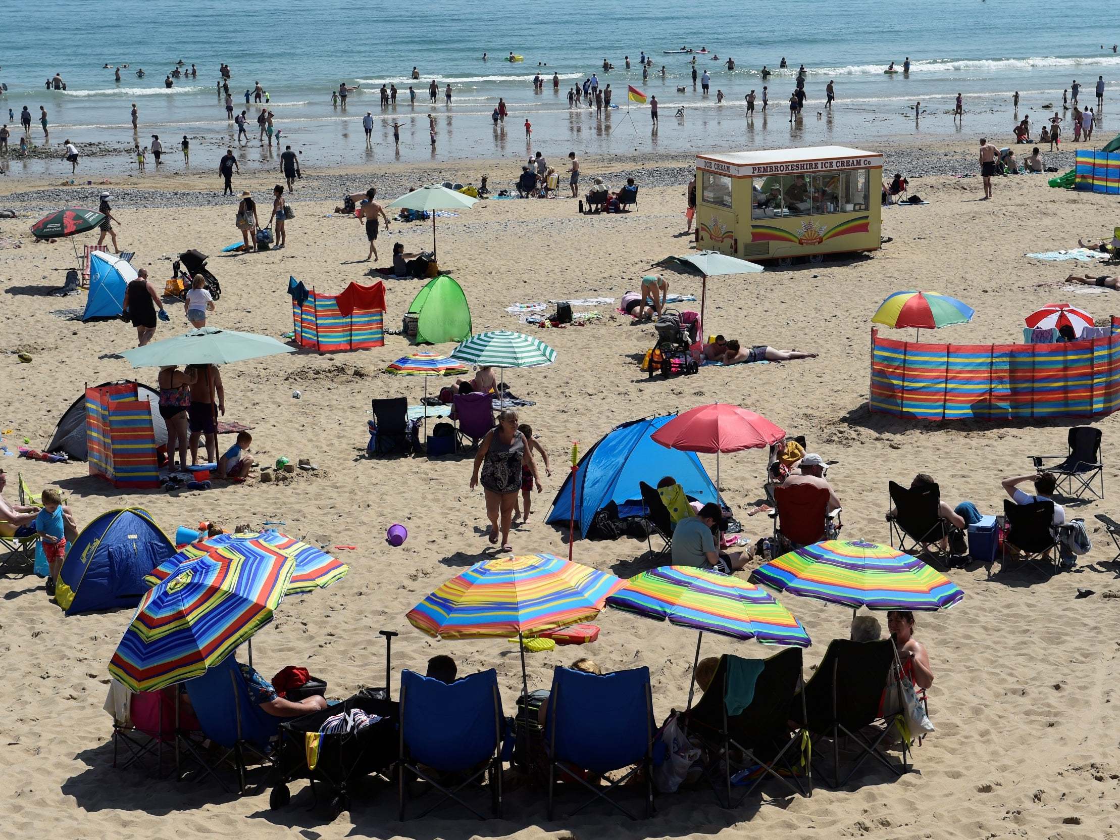 People take shade under umbrellas in Tenby, Pembrokeshire (Reuters/Rebecca Naden)