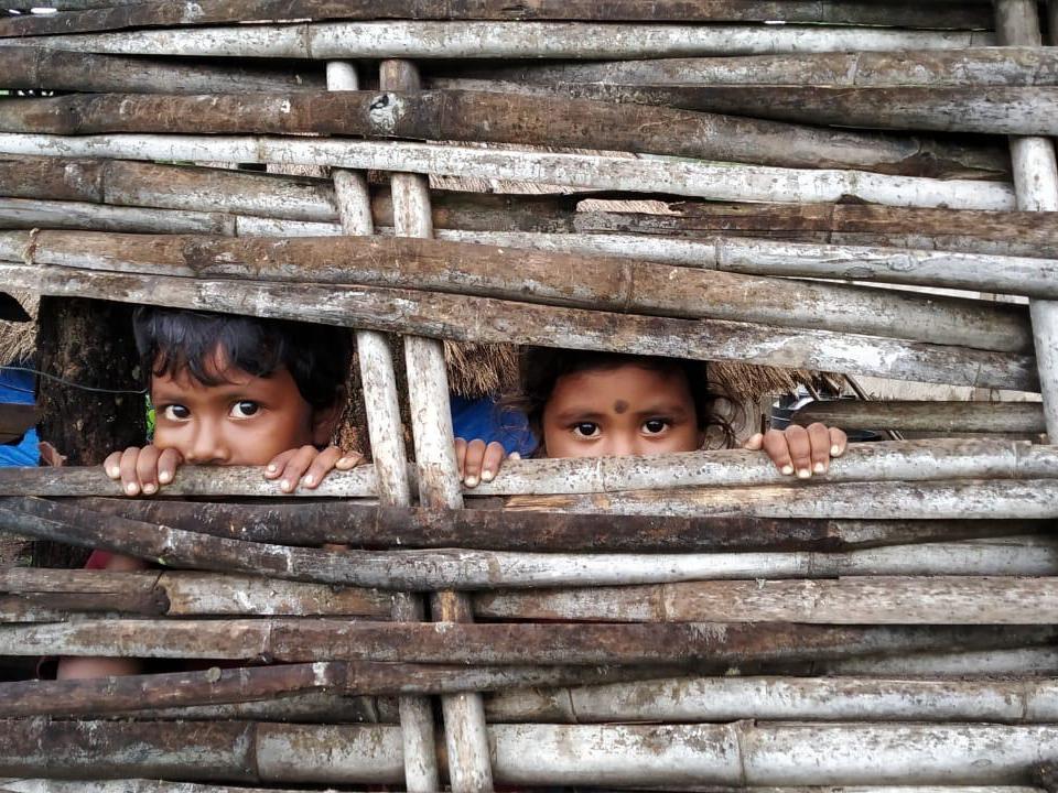 Two Chenchu children look out from their bamboo home in the forests of Telangana. They face an uncertain future