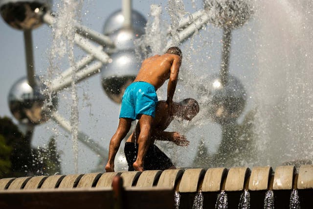 Men cool off in a public fountain near the Atomium in Brussels as parts of Europe see a record-breaking heat wave