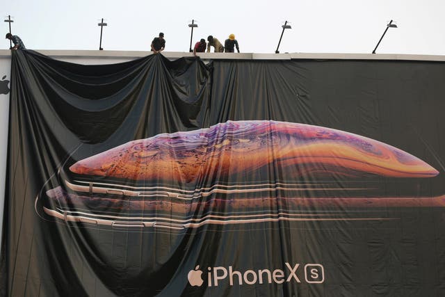 Workers adjust a hoarding of the newly launched iPhone XS in Ahmedabad, India