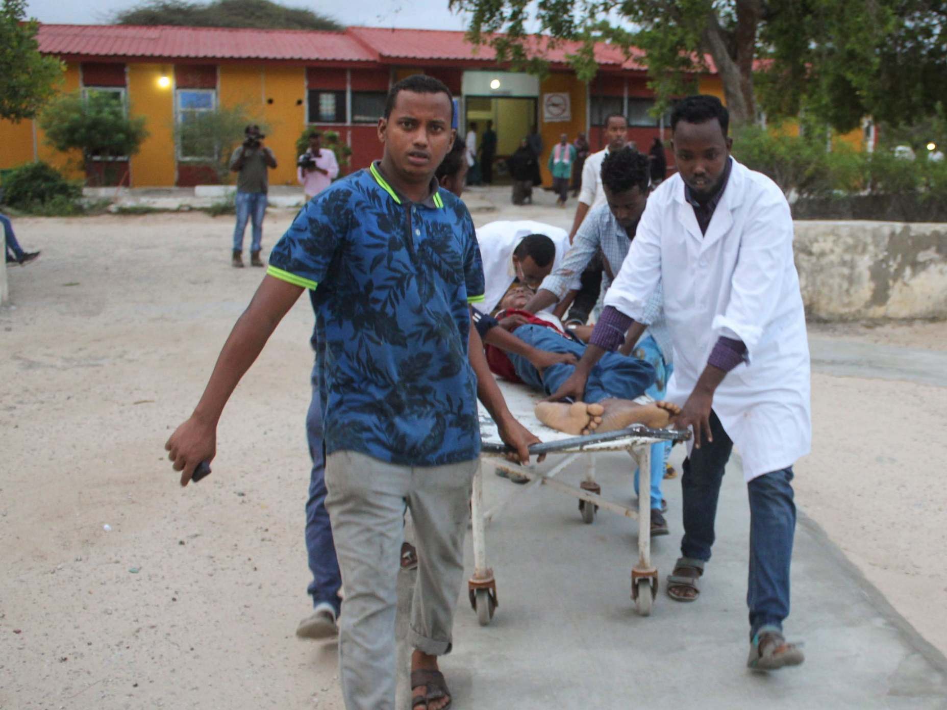 Medics carry a man who was injured in a blast after a suicide bomber walked into the office of Mogadishu's mayor before blowing himself up
