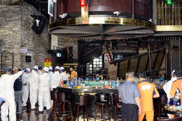 Firefighters and officials examine the collapsed structure of the Coyote Ugly nightclub where several athletes competing at the World Swimming Championships were dancing in the city of Gwangju in South Korea