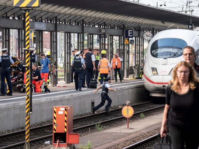 Firefighters and police officers remain on the scene after a child died when he was pushed onto the tracks in front of a train at Frankfurt's main station