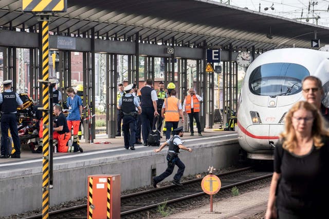 Firefighters and police officers remain on the scene after a child died when he was pushed onto the tracks in front of a train at Frankfurt's main station