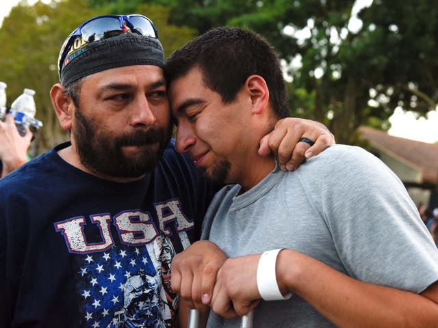 Justin Bates (right), a survivor of the mass shooting, is comforted by his father Rob at a vigil in Gilroy