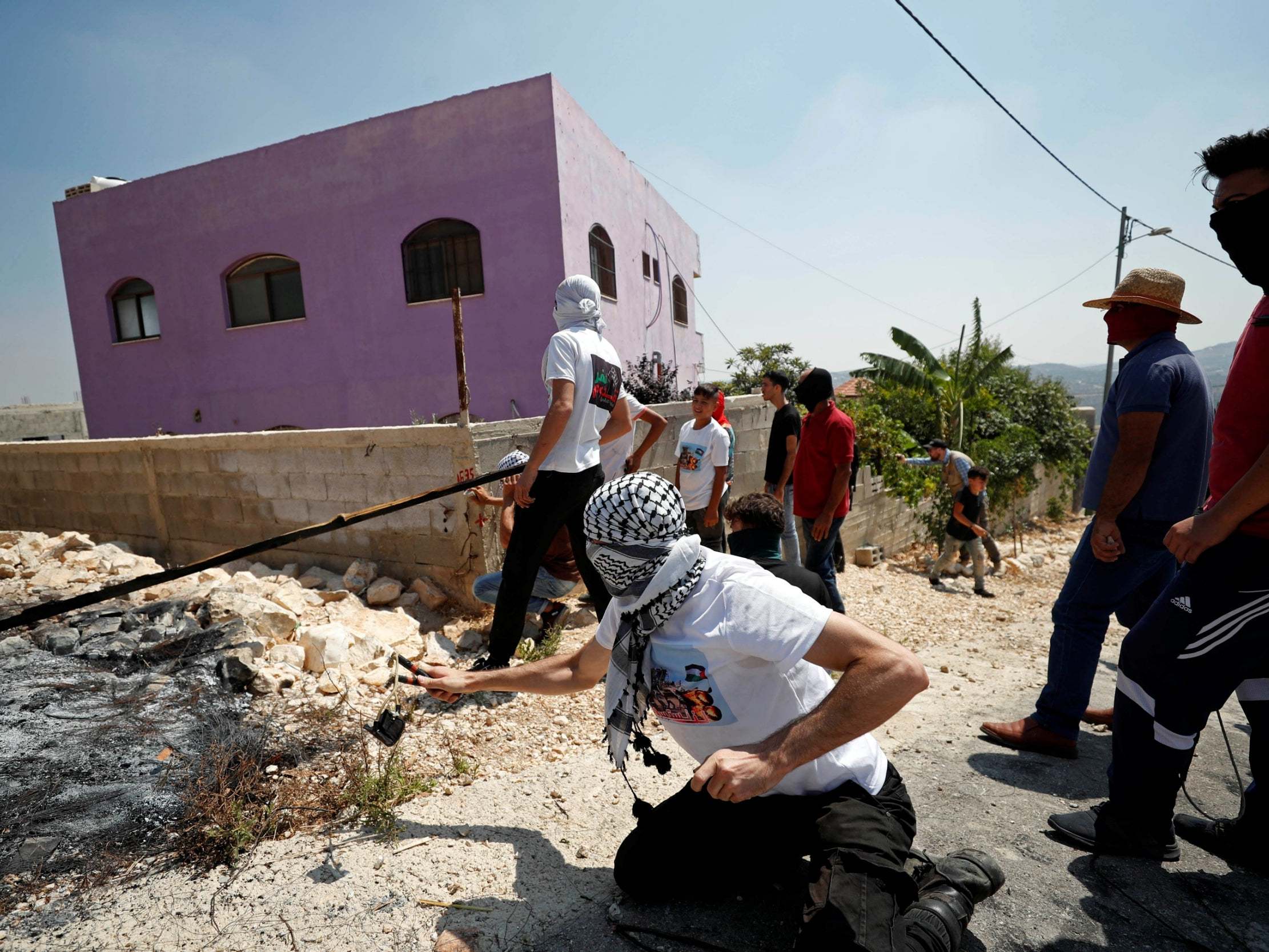 Palestinian demonstrator hurls stones at Israeli forces during July 2019 protest against Jewish settlement of Qadomem in the occupied West Bank