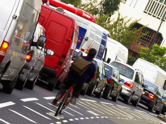 A cyclist make his way through solid traffic in London