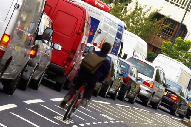 A cyclist make his way through solid traffic in London