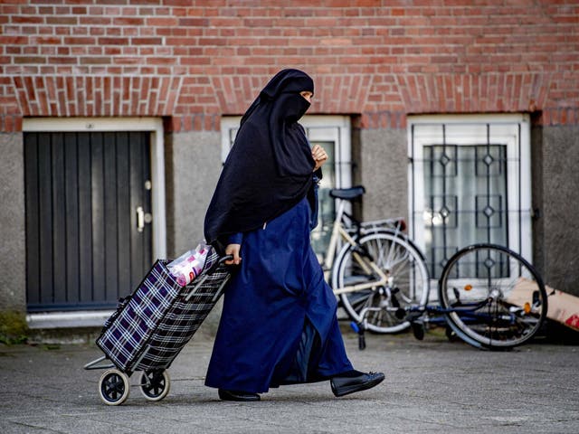 A veiled woman pulls a shopping bag along the street in Rotterdam last month, just before a ban on face coverings came into force