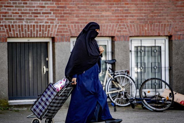 A veiled woman pulls a shopping bag along the street in Rotterdam last month, just before a ban on face coverings came into force