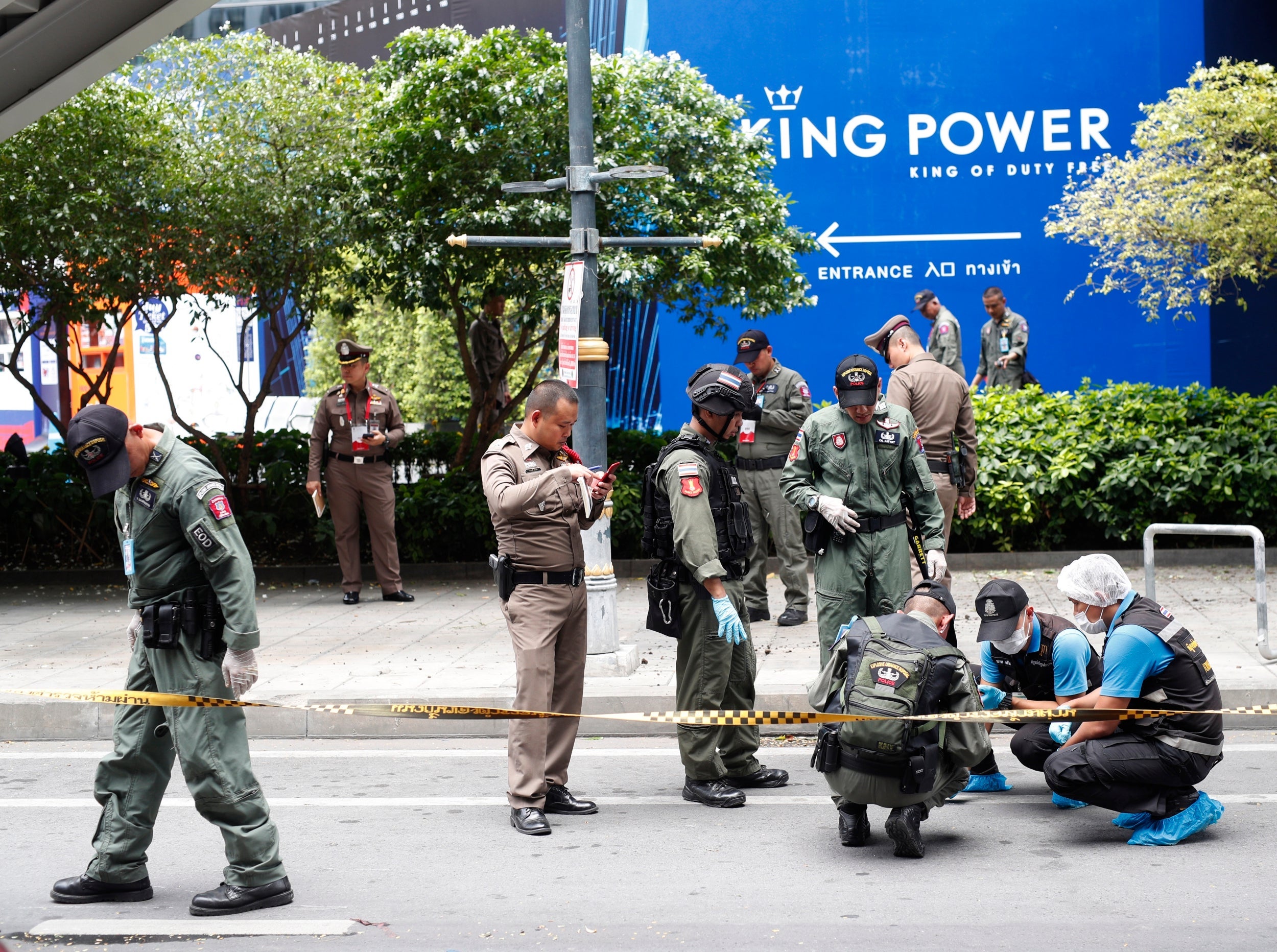 Thai forensic police officers inspect the area where one of a number of small bombs exploded in Bangkok on Friday